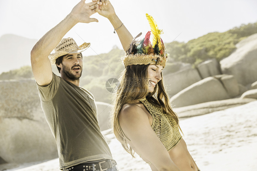戴草帽和羽毛的成年夫妇在海滩上跳舞图片