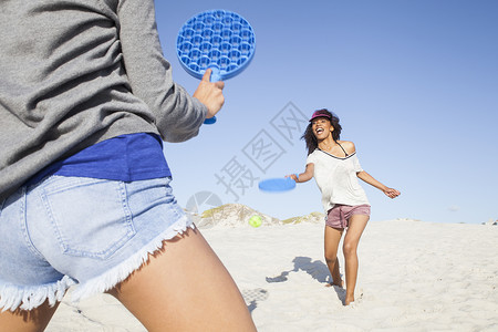 在海滩打网球的女性图片