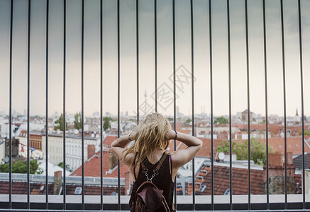 年轻女孩透过栏杆仰望屋顶的风景图片