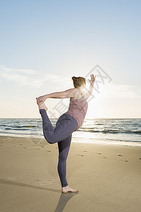 成年女性在日落海滩上做瑜伽姿势图片