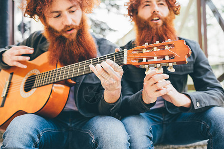 年轻男潮流双胞胎坐着弹吉他图片