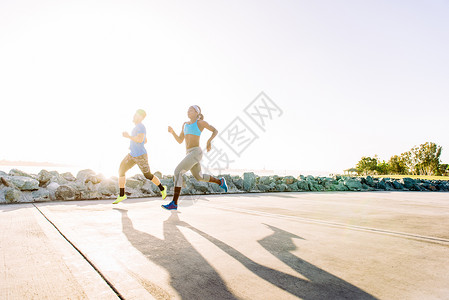 阳光海岸上跑步训练的男女肖像图片