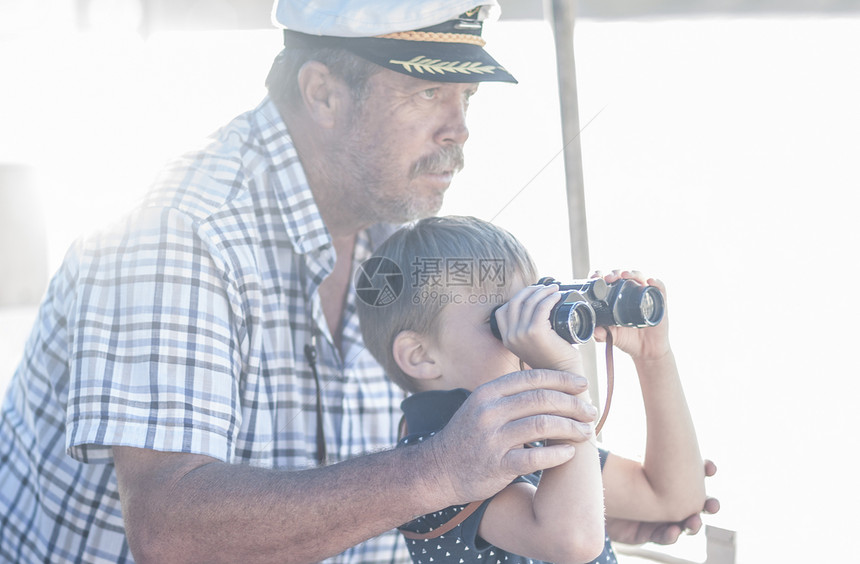 船长和男孩旅游客在乘船旅行时通过望远镜看远方图片