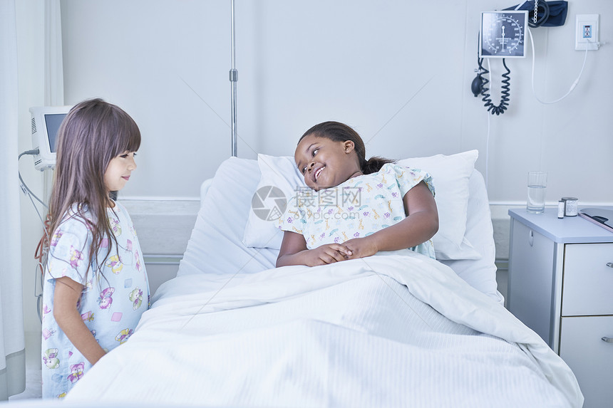 女孩病人在医院儿童房与朋友在床上交谈图片
