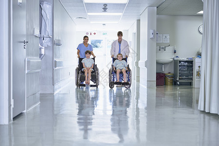 医务人员在医院儿童病房推着轮椅上的男病人图片
