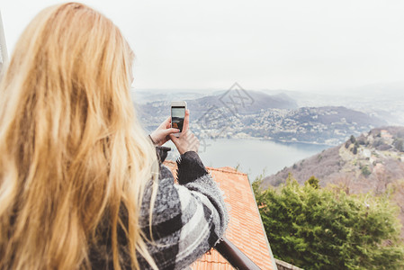 在意大利屋顶露台拍摄迷雾湖的年轻女子图片