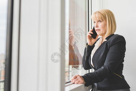 在窗边打电话的女人背景图片