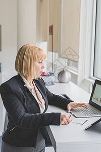 女人在窗边用电脑办公图片