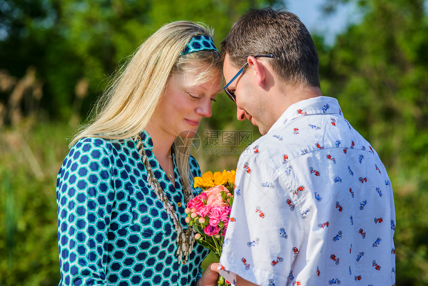 年轻夫妇面对面捧着鲜花图片