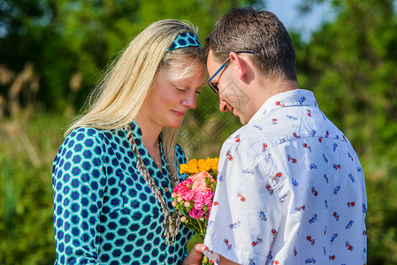 年轻夫妇面对面捧着鲜花图片