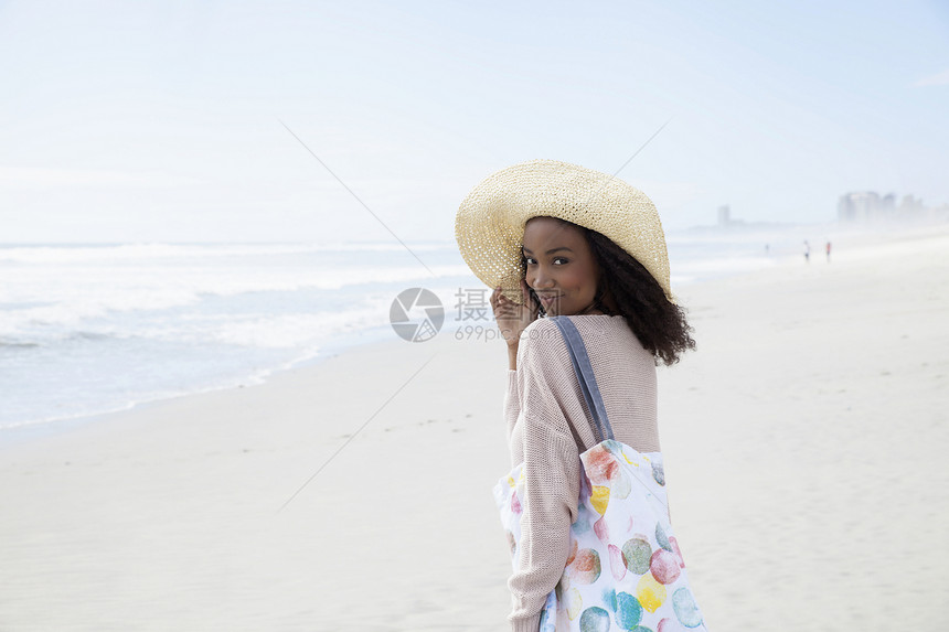 在沙滩上戴帽子的年轻女性图片