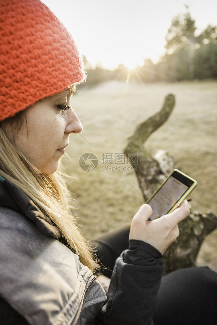 妇女在德国巴伐利亚奥格斯堡在树上休息的女性使用手机图片