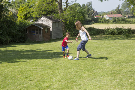 母亲和儿子在花园踢足球图片