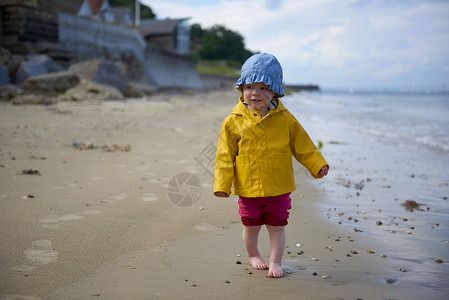 沙滩上身穿防晒衣和雨的小女孩图片