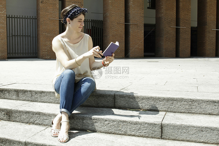 意大利米兰坐在台阶上读笔记本的妇女图片