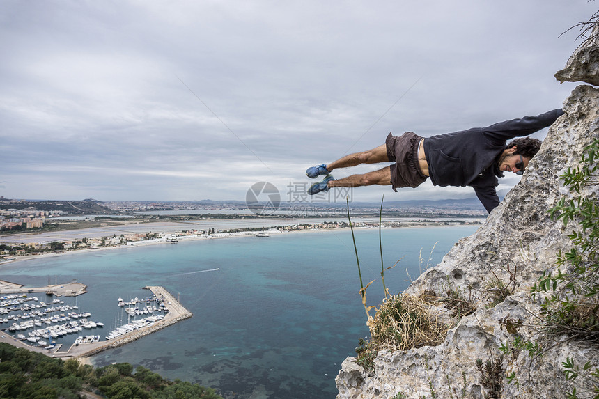 意大利沿海岩石上做极限运动的男登山者图片