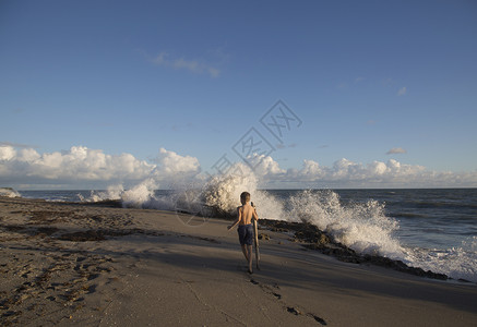 美国佛罗里达州朱庇特岛男孩在浪花飞溅的海滩上探险吹石保护区的后视图背景图片