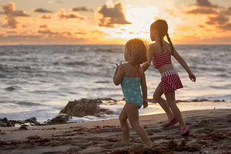 木星海滩女孩和妹在日出时海滩上奔跑美国佛罗里达木星吹落岩保护区背景