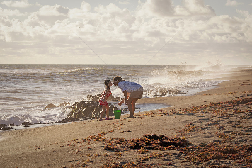 美国佛罗里达州朱庇特岛吹石保护区成熟的女人和女儿在海滩上撅起嘴亲吻图片