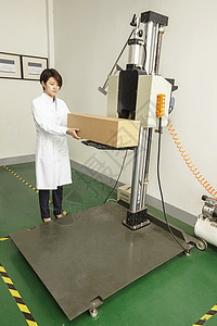 在印刷包装工厂机器上放置纸箱的女技术员图片