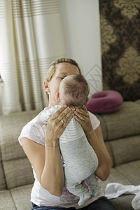 母亲用手支撑婴儿子的头部图片
