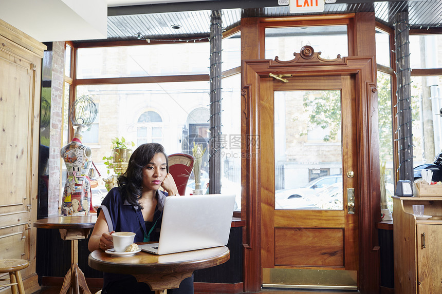 坐在咖啡馆的年轻女性使用笔记本电脑图片