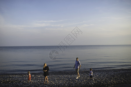 海滩上一家四口一起散步的中年父母图片