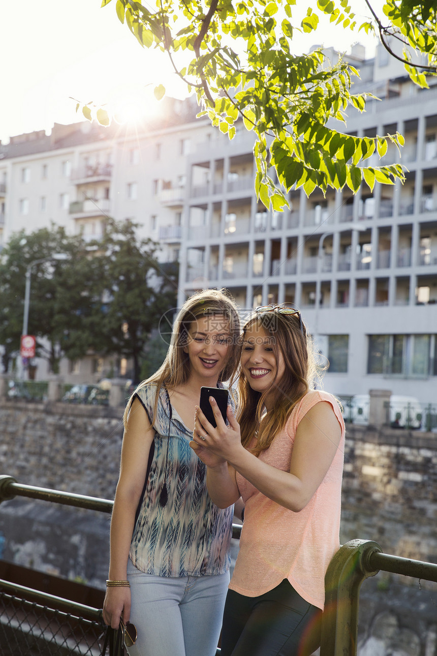 两位成年女性在城市栏杆边使用手机图片