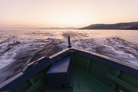 日落时船在海浪上俯首登陆意大利萨丁岛卡波塔加卢拉图片