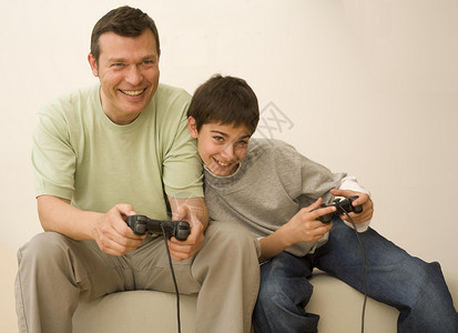 男孩和父亲在沙发上玩游戏控制器图片