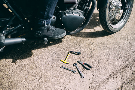 男摩托车手脚和在路上的工具图片