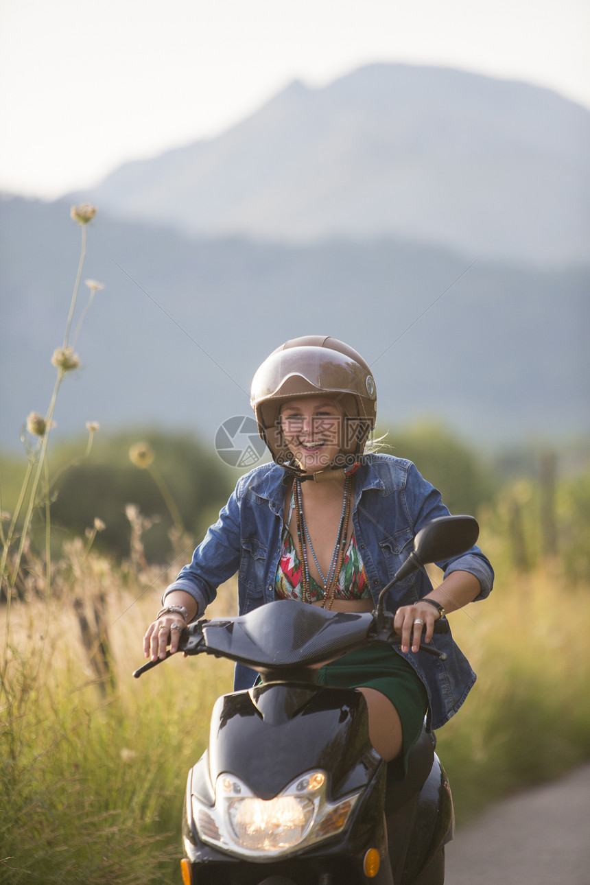 在西班牙马杰卡的农村公路上骑脚踏摩托车的快乐少女图片