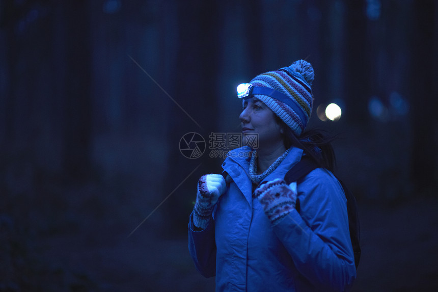 夜间穿戴在森林中横的手电锯徒步女者图片