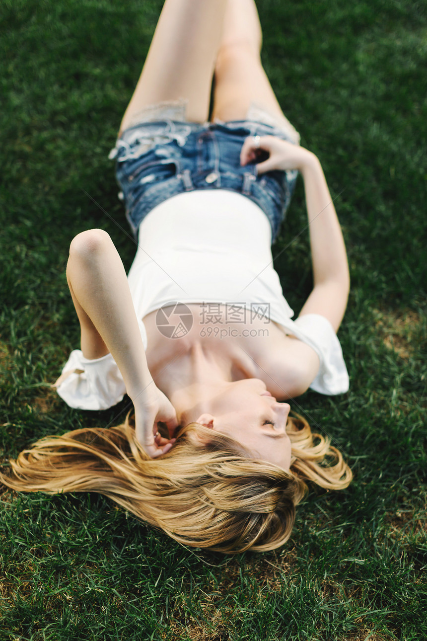 躺在草地上摸头发的年轻女人图片