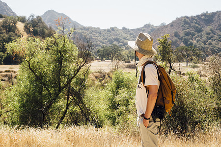 美国加利福尼亚州马里布峡谷徒步旅行的男子眺望远处的山景图片