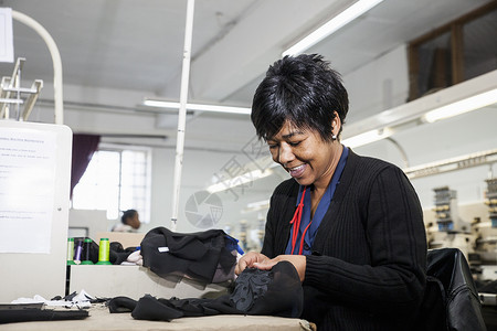 程序化工厂女把黑布缝的线从服装厂速纫机编织的刺绣中除去背景