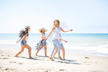 四位成年女朋友在美国加利福尼亚州马里布海滩上玩耍高清图片