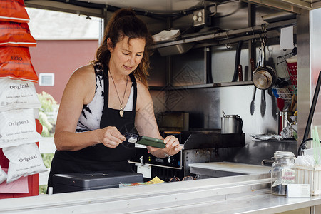 使用智能电话卡阅读器支付食品拖车费用的妇女图片