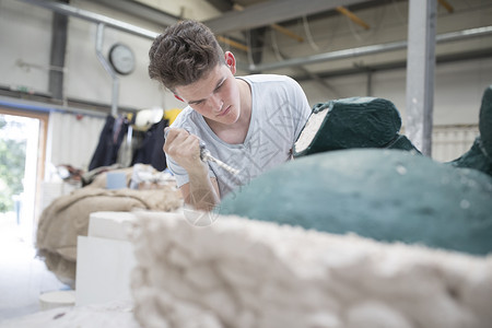 年轻铸造工人在青铜厂去除雕塑的铸模图片