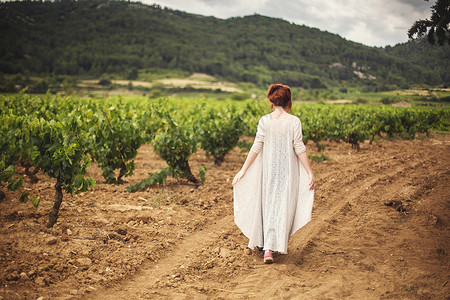 在法国布特纳克的葡萄园后视区走过葡萄园的年轻妇女背景