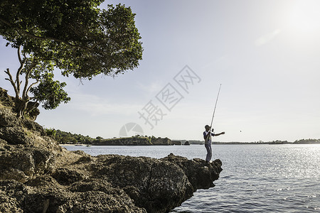印度尼西亚伦博克粉红海滩的岩石捕鱼者图片