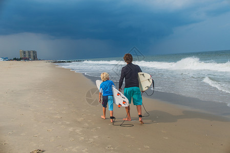 父亲和儿子在海滩上行走图片