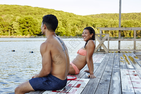 坐在湖边码头的年轻夫妇图片