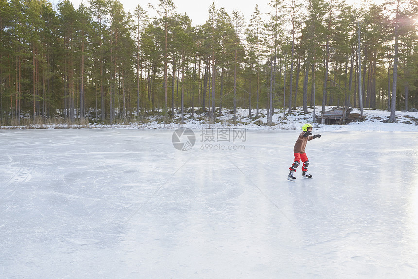 男孩在冰冻湖上滑行图片