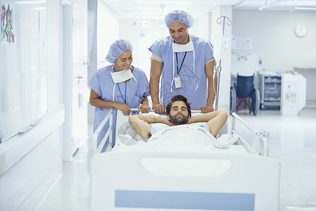 在医院走廊上被护士推着的病床上的男青年病人图片