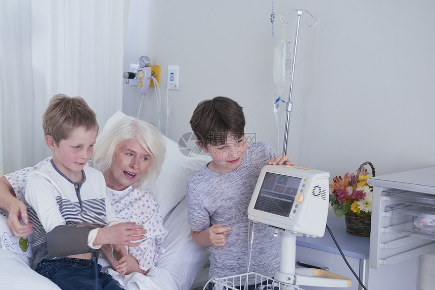 女病人在医院床上与孙子一起看血压机图片