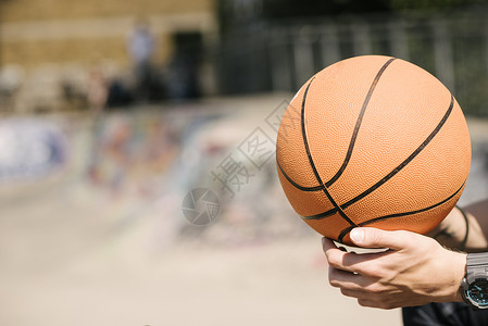 青年男子手握篮球在城市篮球场,运动，背景图片