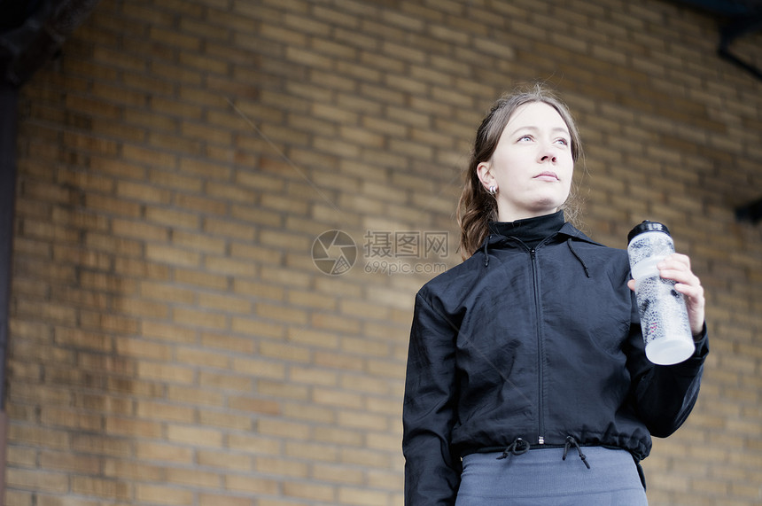 年轻女跑步用瓶装水的肖像图片