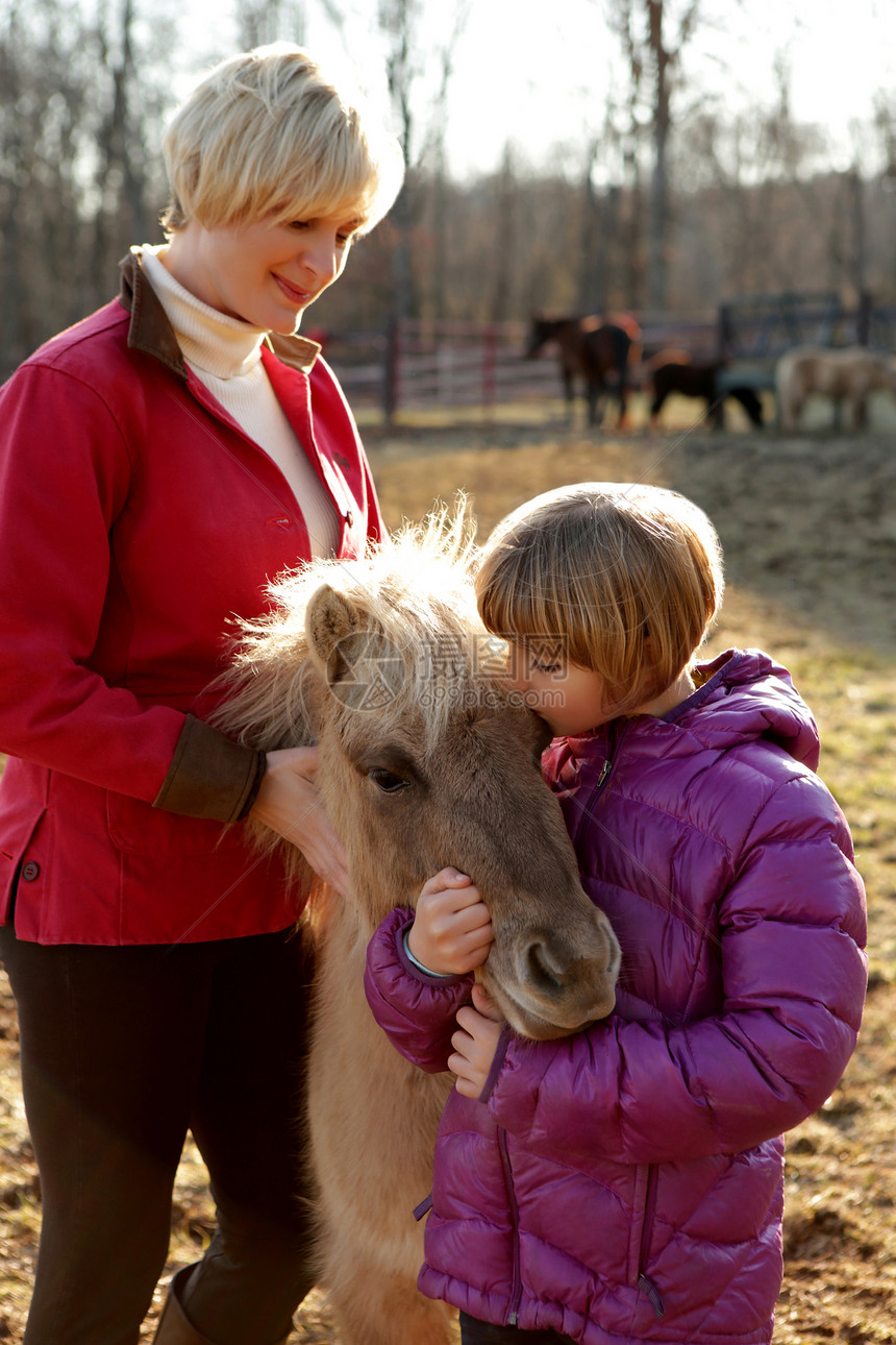 母亲和女儿户外的肖像与小马站在一起图片