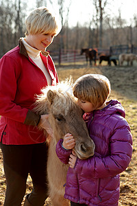 母亲和女儿户外的肖像与小马站在一起图片